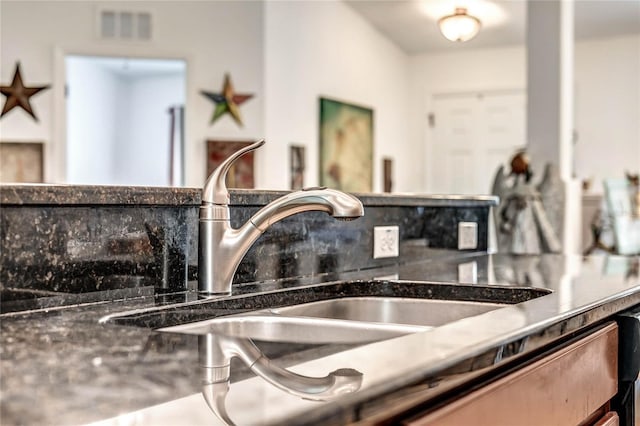 room details with dark stone countertops, decorative backsplash, and sink