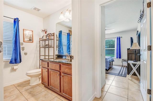 bathroom featuring tile patterned floors, vanity, ceiling fan with notable chandelier, and toilet