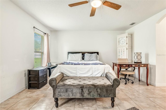 bedroom featuring ceiling fan, light tile patterned floors, and a textured ceiling