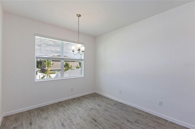 spare room with wood-type flooring and a chandelier