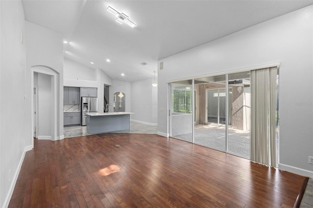 unfurnished living room with high vaulted ceiling and wood-type flooring