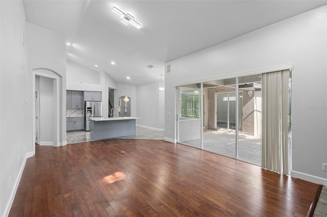 unfurnished living room featuring dark hardwood / wood-style flooring and high vaulted ceiling