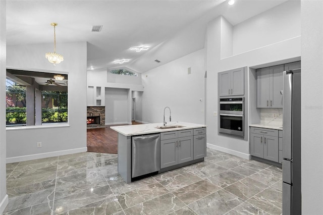 kitchen featuring gray cabinetry, appliances with stainless steel finishes, a fireplace, and sink