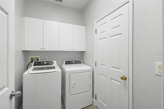 clothes washing area with cabinets and washing machine and dryer