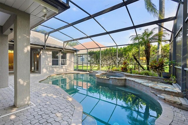 view of swimming pool featuring glass enclosure, a patio, and an in ground hot tub