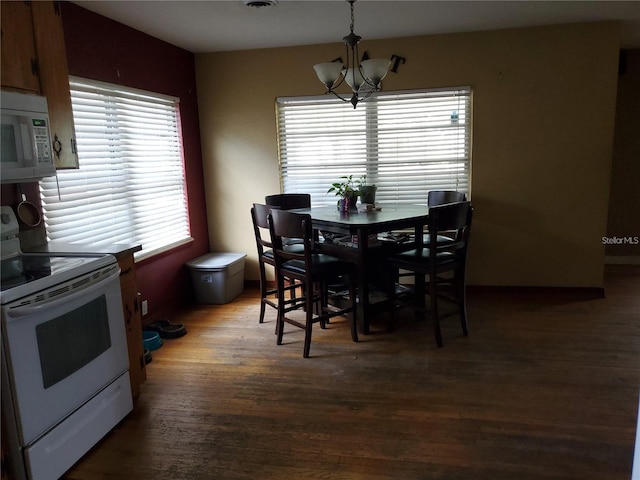 dining area featuring a healthy amount of sunlight, hardwood / wood-style floors, and a notable chandelier