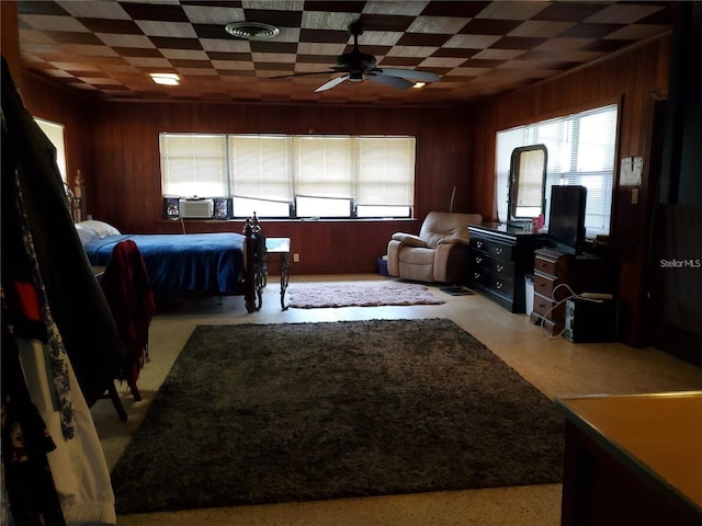 bedroom with cooling unit, wooden walls, and ceiling fan