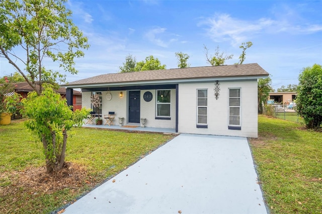 single story home with brick siding, covered porch, a front yard, and fence