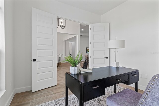 office space featuring an inviting chandelier and light wood-type flooring