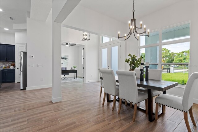 dining area with light hardwood / wood-style flooring and ceiling fan with notable chandelier