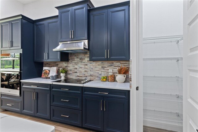 kitchen featuring decorative backsplash, blue cabinets, and black electric cooktop