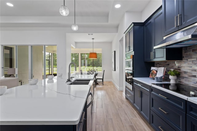 kitchen featuring hanging light fixtures, sink, tasteful backsplash, and light wood-type flooring