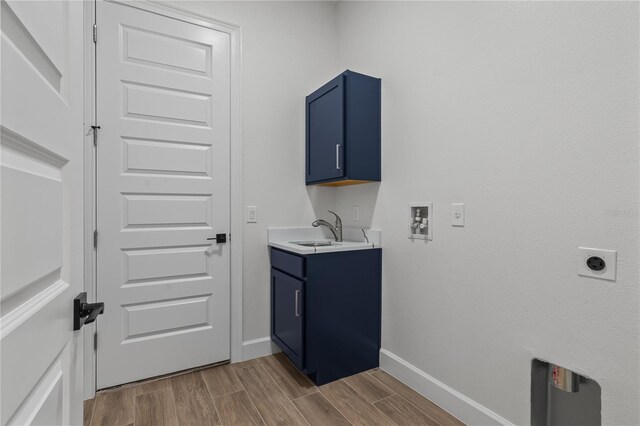 laundry room featuring sink, electric dryer hookup, cabinets, light hardwood / wood-style flooring, and washer hookup