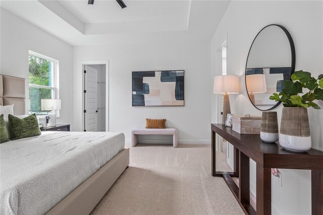 carpeted bedroom with ceiling fan and a raised ceiling