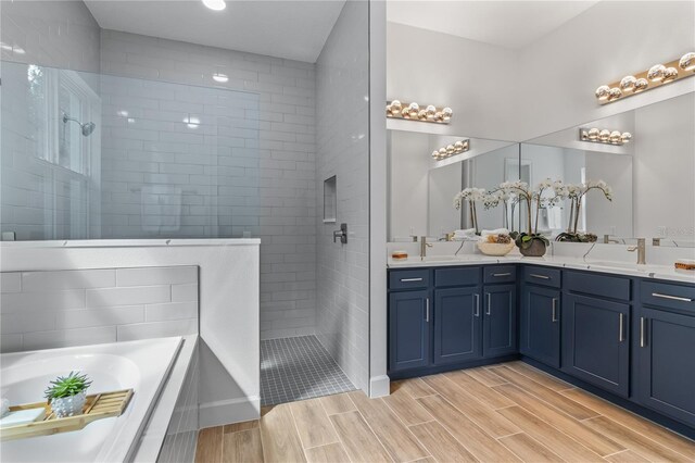 bathroom featuring double sink vanity, hardwood / wood-style floors, and separate shower and tub