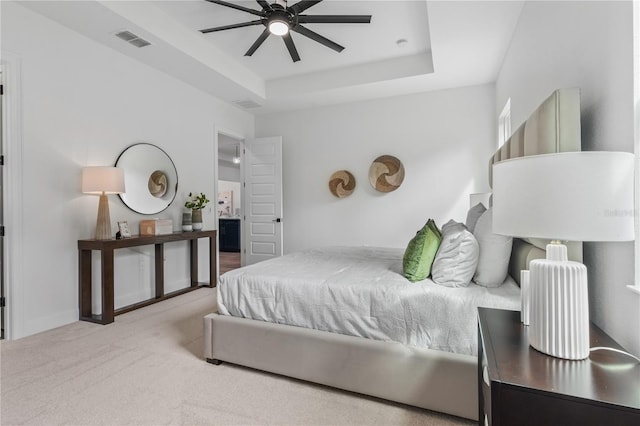 carpeted bedroom featuring ceiling fan and a tray ceiling