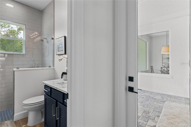 bathroom featuring tiled shower, vanity, hardwood / wood-style flooring, and toilet