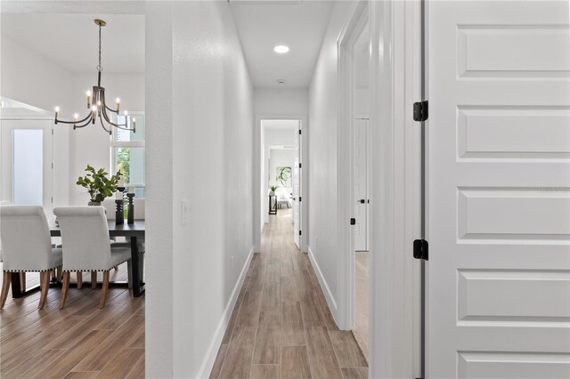 hallway with hardwood / wood-style flooring and a chandelier