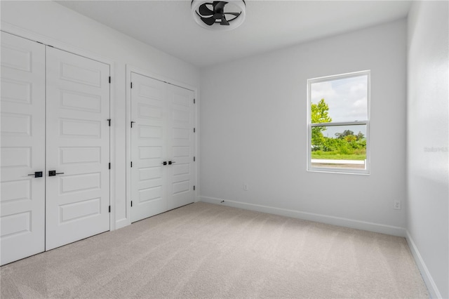 unfurnished bedroom featuring multiple closets and carpet