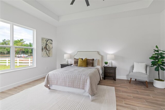 bedroom featuring a tray ceiling, light hardwood / wood-style floors, and ceiling fan