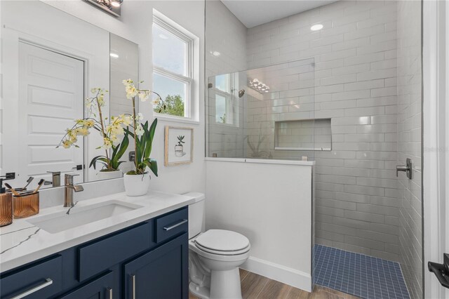 bathroom featuring vanity, tiled shower, toilet, and hardwood / wood-style floors