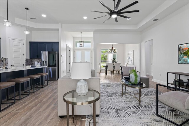 living room with a high ceiling, light wood-type flooring, and a tray ceiling