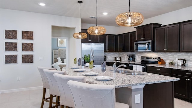 kitchen featuring sink, stainless steel appliances, pendant lighting, and an island with sink