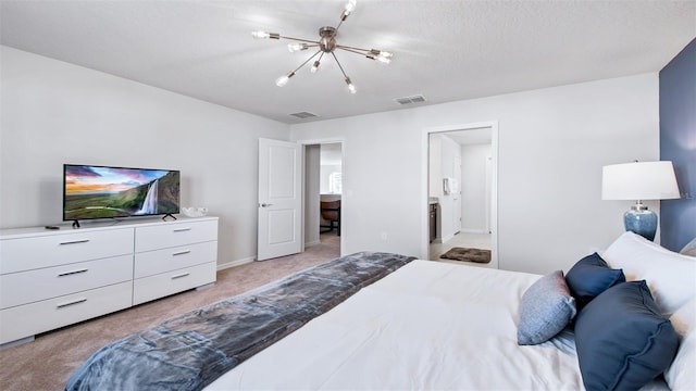 carpeted bedroom with ensuite bath, a chandelier, and a textured ceiling