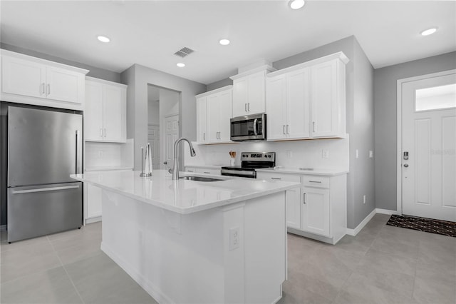 kitchen featuring white cabinets, sink, an island with sink, and stainless steel appliances