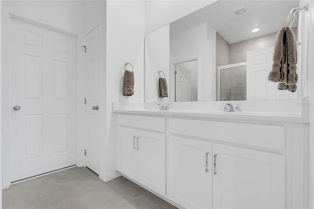 bathroom featuring a shower with door and vanity