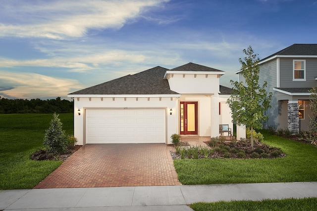 view of front of home with stucco siding, a front lawn, decorative driveway, and roof with shingles