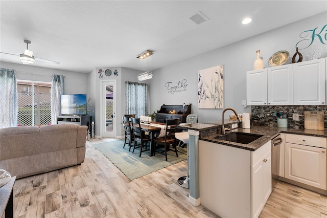 kitchen with white cabinetry, sink, light wood-type flooring, and kitchen peninsula