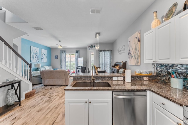 kitchen featuring sink, white cabinets, backsplash, dark stone counters, and stainless steel dishwasher