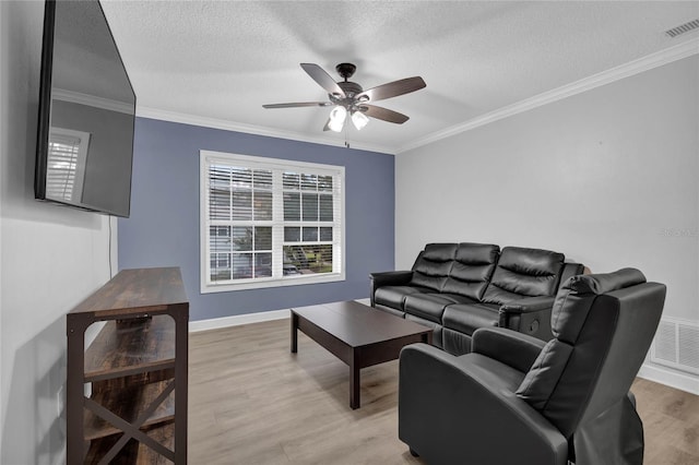 living room with ceiling fan, light hardwood / wood-style flooring, ornamental molding, and a textured ceiling