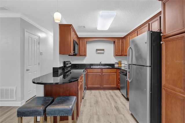 kitchen featuring hanging light fixtures, a kitchen breakfast bar, light hardwood / wood-style flooring, ornamental molding, and stainless steel appliances