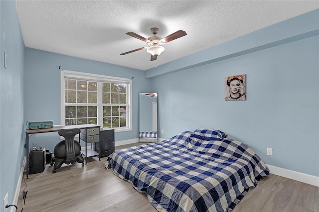 bedroom with light hardwood / wood-style floors, a textured ceiling, and ceiling fan