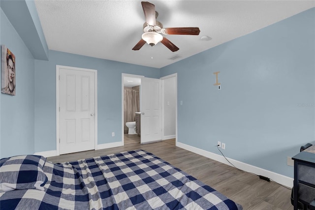 bedroom featuring ceiling fan, hardwood / wood-style floors, ensuite bathroom, and a textured ceiling