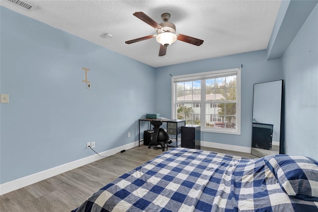 bedroom featuring light hardwood / wood-style floors, a textured ceiling, and ceiling fan