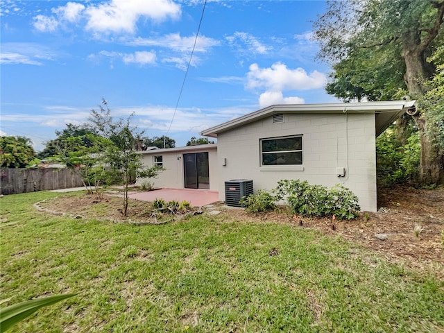 rear view of property featuring central air condition unit, a patio area, and a lawn