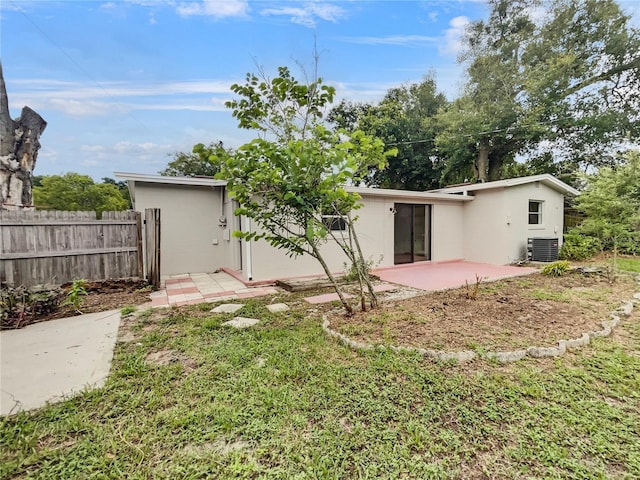 rear view of property featuring a patio, central AC unit, and a lawn