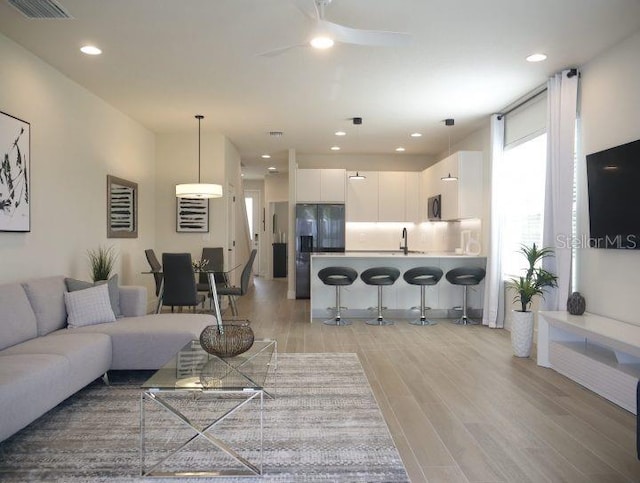 living room featuring light hardwood / wood-style floors and ceiling fan