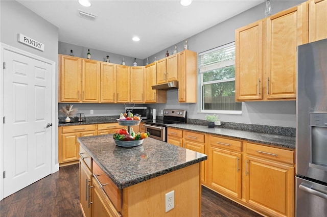 kitchen with stainless steel appliances, a center island, dark stone countertops, and dark hardwood / wood-style floors