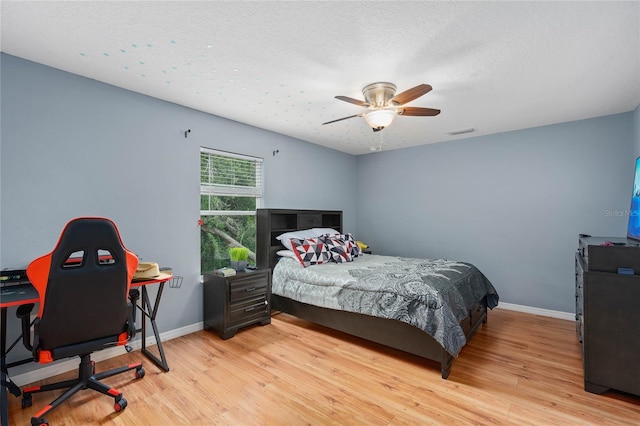 bedroom with ceiling fan, a textured ceiling, and light wood-type flooring