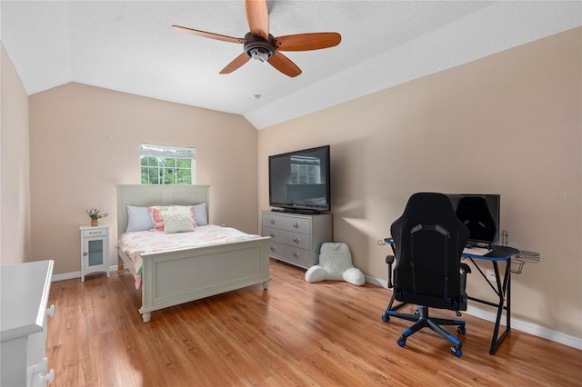 bedroom with lofted ceiling, a textured ceiling, light hardwood / wood-style floors, and ceiling fan