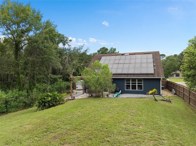 back of property featuring a yard, a patio, and solar panels