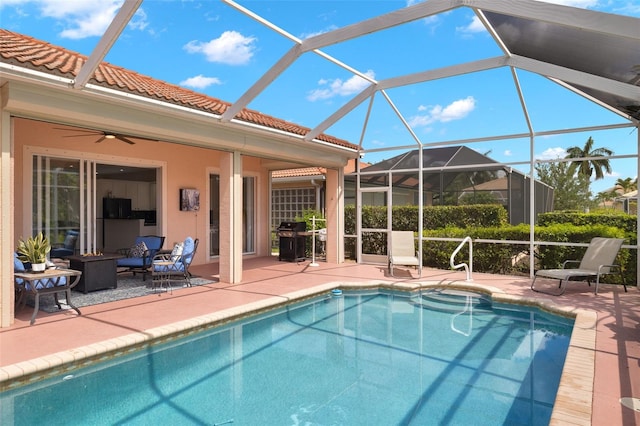 view of swimming pool featuring ceiling fan, a lanai, grilling area, and a patio area