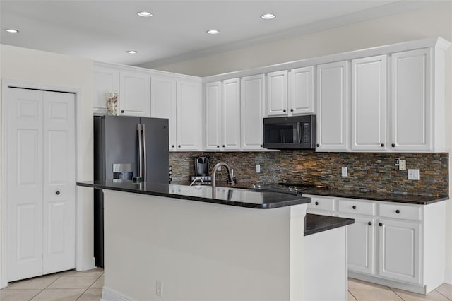 kitchen with white cabinetry, stainless steel fridge, light tile patterned floors, decorative backsplash, and a kitchen island