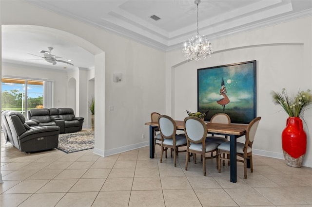 tiled dining space featuring crown molding, ceiling fan with notable chandelier, and a tray ceiling