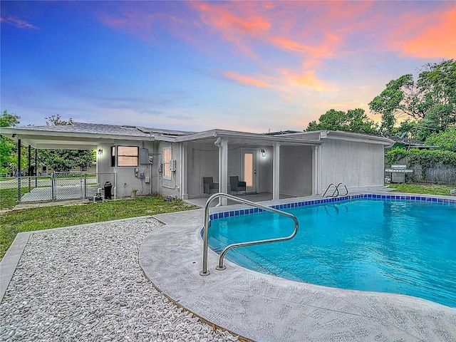 pool at dusk featuring a patio