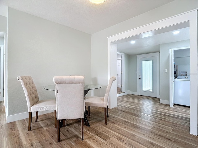 dining space with washer / dryer, light hardwood / wood-style floors, and a textured ceiling